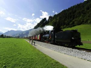 Ein Zug fährt die Gleise entlang eines Feldes in der Unterkunft Gästehaus Flörl in Gerlosberg