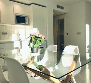 uma mesa de vidro com cadeiras brancas e um vaso com flores em Domus Apartamentos Granada con parking gratuito en pleno centro em Granada