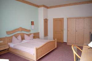 Schlafzimmer mit einem Holzbett mit weißer Bettwäsche und rosa Kissen in der Unterkunft Pension Haus Marga in Wernigerode