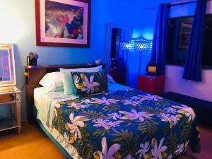 ein blaues Schlafzimmer mit einem Bett mit einer bunten Decke in der Unterkunft Kona Magic Honu Room in Kailua-Kona