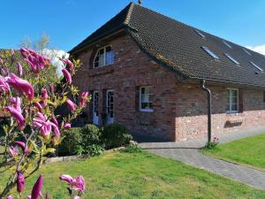 een bakstenen huis met roze bloemen ervoor bij Boddenhus auf Rügen - Ferienwohnungen und Pension in Rappin