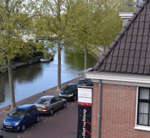 drei Autos auf einem Parkplatz neben einem Fluss geparkt in der Unterkunft Het Hart van Weesp in Weesp