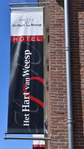 ein Schild für ein Hotel an der Seite eines Backsteingebäudes in der Unterkunft Het Hart van Weesp in Weesp