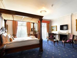 um quarto com uma cama de dossel e uma televisão em Grand Royale Hyde Park em Londres