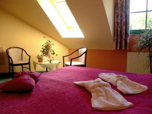 a bedroom with a pink bed with two robes on it at Oder-Hotel in Schwedt