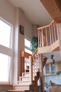 a wooden staircase in a room with two windows at Artists Residence Liepāja in Liepāja