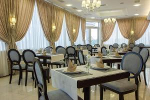 un comedor con mesas, sillas y cortinas en Alarus Luxe Hotel, en Odessa