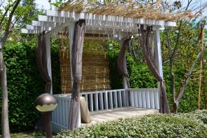 um gazebo com um banco num jardim em Milennia Family Hotel em Sunny Beach