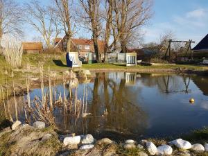 um lago num quintal com árvores e uma casa em Birkenhof Neuharlingersiel em Neuharlingersiel