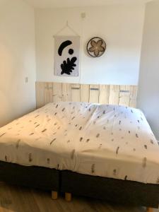 een bed in een slaapkamer met een klok aan de muur bij Puur Texels 6 in De Koog