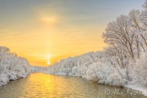 a river with snow covered trees and the sunset at Alpine Inn & Suites Gunnison in Gunnison