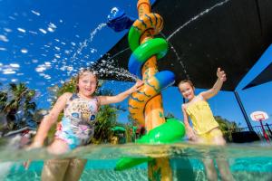 dos niños jugando en un tobogán acuático en un parque acuático en Lakeside Forster Holiday Park and Village, en Forster