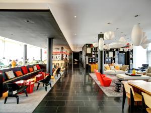 un hall avec des chaises et des tables rouges dans un bâtiment dans l'établissement citizenM Paris Charles de Gaulle Airport, à Roissy-en-France