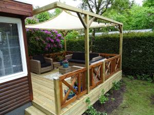 a wooden deck with a gazebo at vakantiehuis op de veluwe in Wolfheze