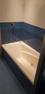 a white bath tub in a bathroom with blue tiles at Sur Hotel in Montevideo