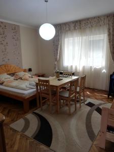 ein Esszimmer mit einem Tisch, Stühlen und einem Bett in der Unterkunft Csilla Apartman in Makó