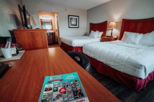 une chambre d'hôtel avec deux lits et un livre sur une table dans l'établissement Lamplighter Inn and Suites - North, à Springfield