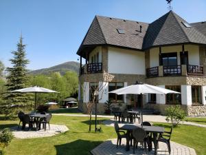 une grande maison avec des tables et des parasols dans la cour dans l'établissement Садиба "Градний Узвіз", à Tatariv