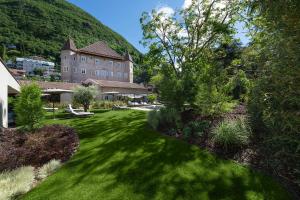 een groene tuin met een groot gebouw op de achtergrond bij Castel Hörtenberg in Bolzano