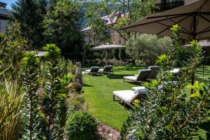 een tuin met ligstoelen en een parasol bij Castel Hörtenberg in Bolzano