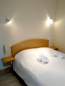 a bedroom with a white bed with two towels on it at Hôtel des Sables Blancs in Douarnenez