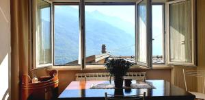 een tafel in een kamer met een groot raam bij Casa vista Saint Vincent accanto alle Terme in Saint Vincent