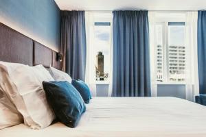 una camera da letto con letto, cuscini e finestra di Amsterdam Beach Hotel a Zandvoort