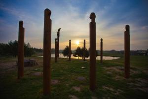 a group of poles in a field with the sunset in the background at Baltas gandras in Naisiai