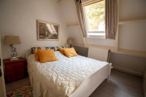 a bedroom with a bed with yellow pillows and a window at Casita Boschberg in Biddinghuizen