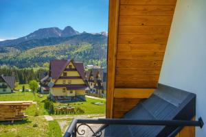 balcone con vista su un villaggio e sulle montagne. di Widokówka Tatry Pokoje i Apartamenty a Kościelisko