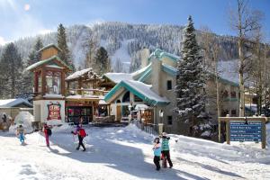 un groupe de personnes debout dans la neige devant un lodge de ski dans l'établissement Alpine Village Suites, à Taos Ski Valley