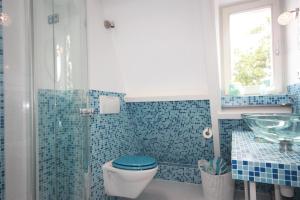 een blauw betegelde badkamer met een toilet en een wastafel bij De Pimpelmees in Den Haag