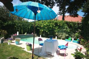 een tafel met een blauwe parasol naast een zwembad bij De Pimpelmees in Den Haag