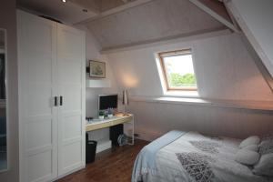 een slaapkamer met een bed, een bureau en een raam bij De Pimpelmees in Den Haag