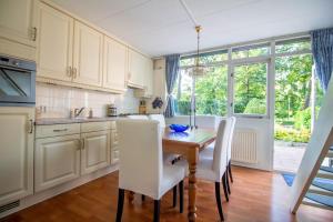 a kitchen with a wooden table and white chairs at Casita Boschberg in Biddinghuizen