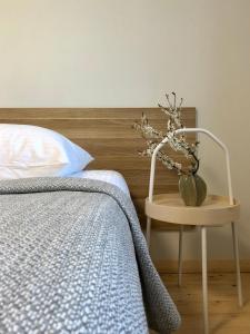 - une chambre avec un lit et une table ornée d'un vase de fleurs dans l'établissement COMFY Patogūs namai, à Kaunas