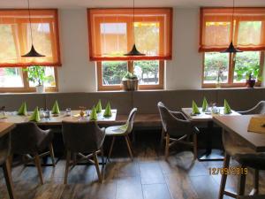 - une salle à manger avec des tables, des chaises et des fenêtres dans l'établissement Aparthotel Garni Schranz, à Wald im Pinzgau