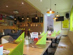 un restaurant avec des tables en bois et du papier vert sur elles dans l'établissement Aparthotel Garni Schranz, à Wald im Pinzgau