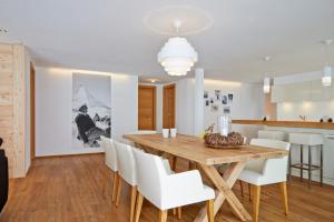 a dining room with a wooden table and white chairs at Hörnligrat Apartments in Zermatt