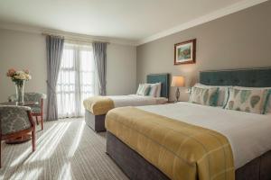 a hotel room with two beds and a table with a chair at Killarney Heights Hotel in Killarney