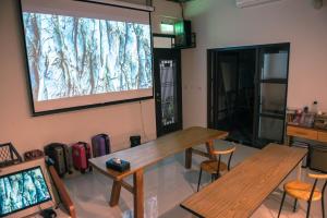 une chambre avec deux tables et un écran de projection dans l'établissement Happy Wing Guesthouse, à Hualien