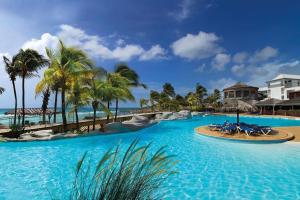 una grande piscina con palme e un resort di Magnifique appartement avec Vue Mer, Accès Direct à la Plage et Piscine surveillée a Saint-François