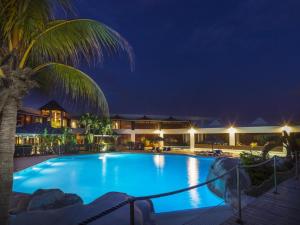 una piscina notturna con una palma di Magnifique appartement avec Vue Mer, Accès Direct à la Plage et Piscine surveillée a Saint-François