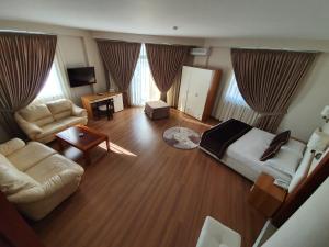 een slaapkamer met een bed, een bank en een tafel bij Hotel Arvi in Durrës