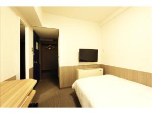 une chambre d'hôtel avec un lit et une télévision dans l'établissement Sendai Business Hotel Ekimae, à Sendai