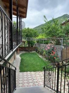 a balcony of a house with a yard with flowers at Guest House IBERIA in Mtskheta