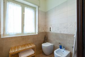 a bathroom with a toilet and a sink and a window at Villa Viuli in Torre del Greco