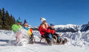 a group of people riding on a sled in the snow at Pension Patricia in Kaprun