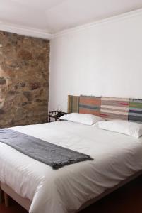 a bedroom with a large white bed with a stone wall at Casa de Campo Alter Pedroso in Alter do Chão