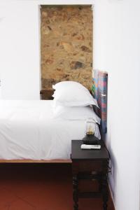 a bed with white sheets and a table with a clock on it at Casa de Campo Alter Pedroso in Alter do Chão